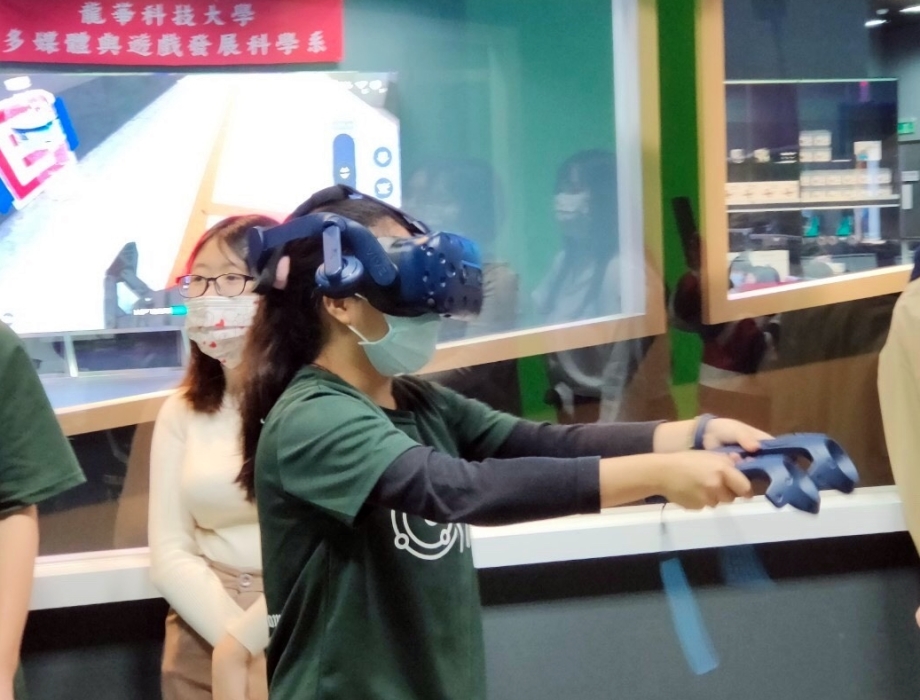 高中參賽者戴上VR眼鏡，在數位內容中心體驗遊戲系學生所設計遊戲作品。