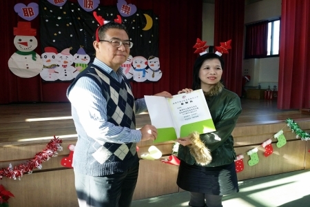 圖為龍壽國小校長張雅筑對龍華科大表達由衷謝意，並致贈感謝狀給應外系師生，由計畫主持人何台華教授代表接受。