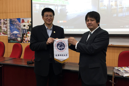 圖為龍華科大觀光系主任胡光復(左)，致贈校旗予日方代表三重縣觀光局谷德彥(TANI Norihiko)。