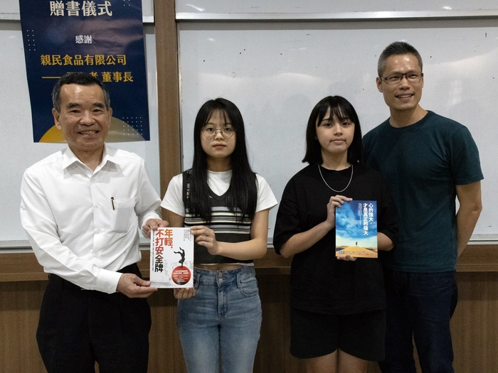 親民實業董事長張存孝(左)，致贈許峰源律師著作給現場聆聽演講的幸運獲獎同學。